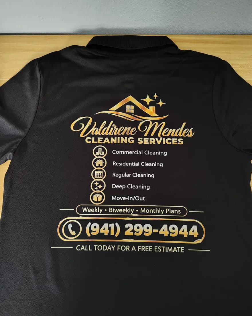 Black polo with the Valdirene Mendes Cleaning Services logo, service list and phone number on the back